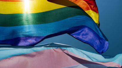 gay and transgender pride flags waving on the sky