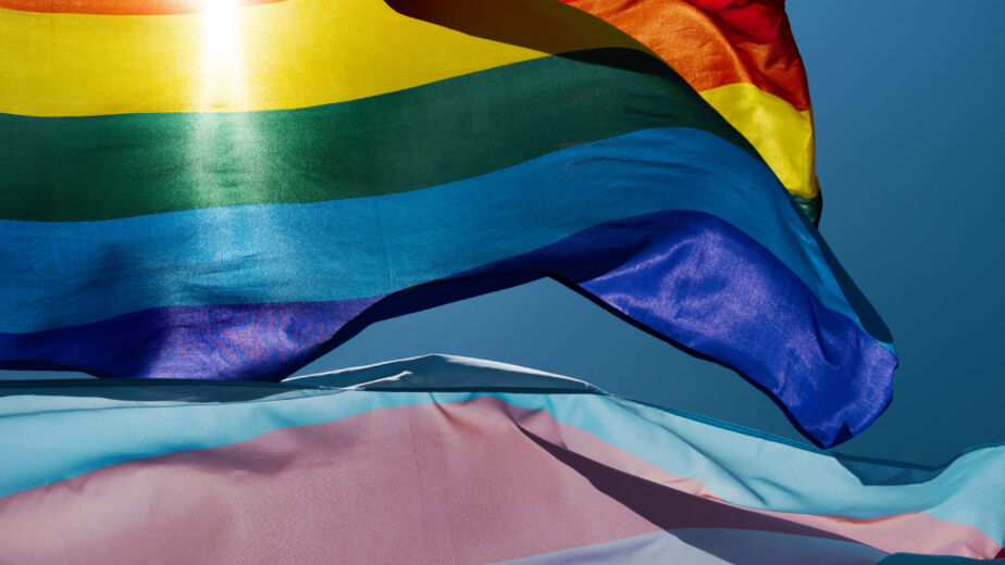 gay and transgender pride flags waving on the sky